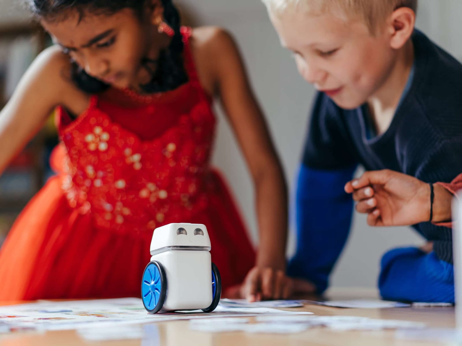 The KUBO robot driving across TagTiles on a desk while two students watch